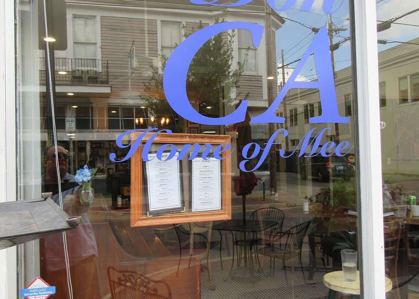 Large blue vinyl lettering applied to a café's glass window with tables visible inside