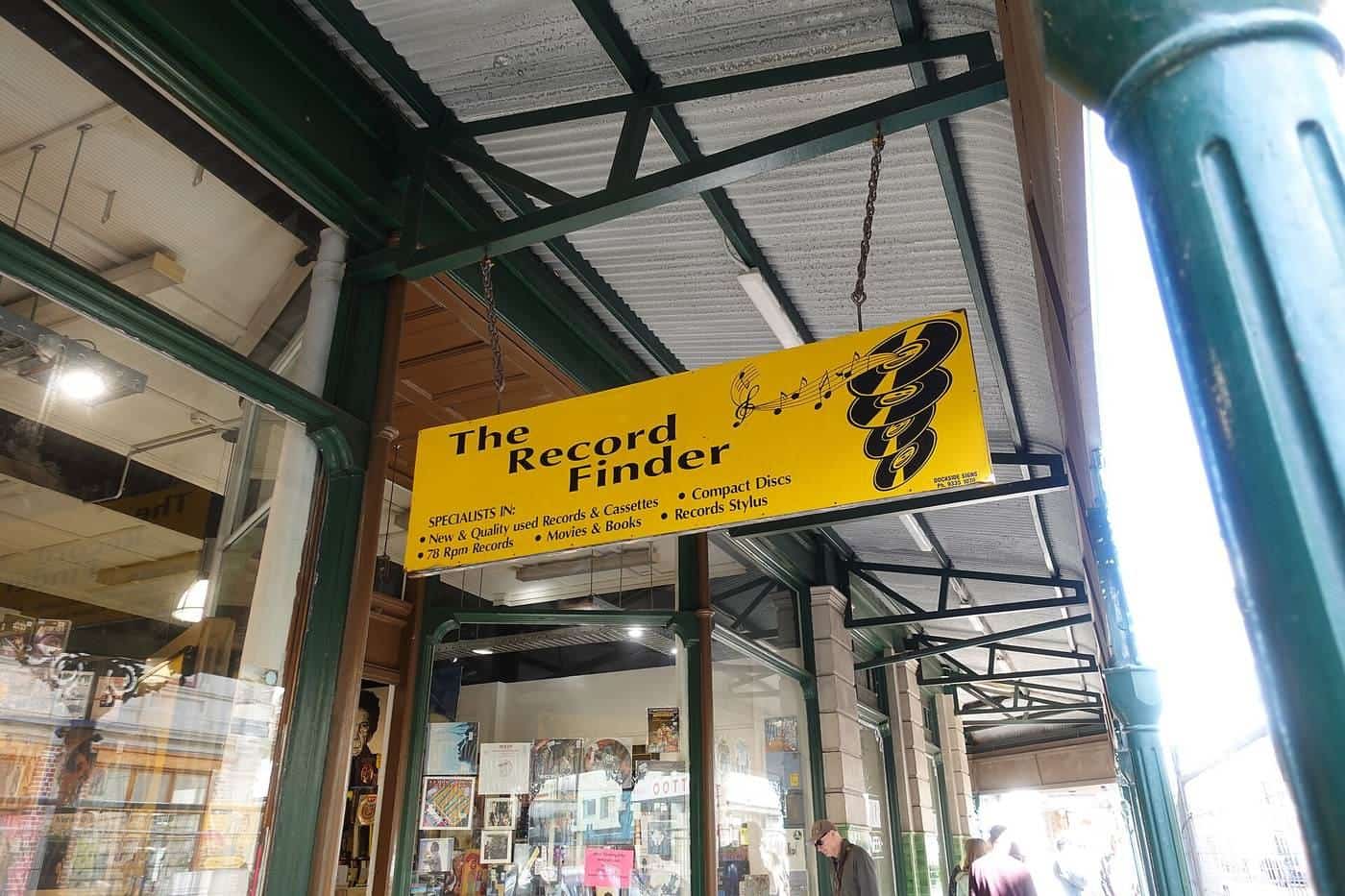 A bright yellow hanging shop sign under a verandah on a Fremantle street